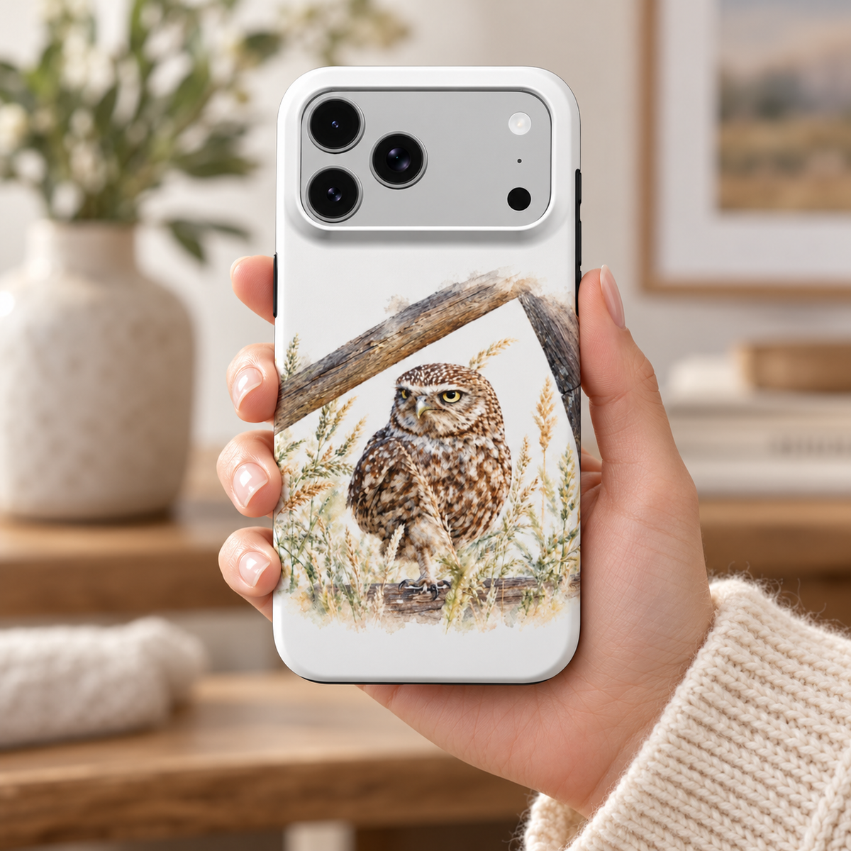 iPhone-hoesje met Steenuil in aquarelstijl in de hand, met de bedrukte achterkant en camera-uitsparing zichtbaar.
