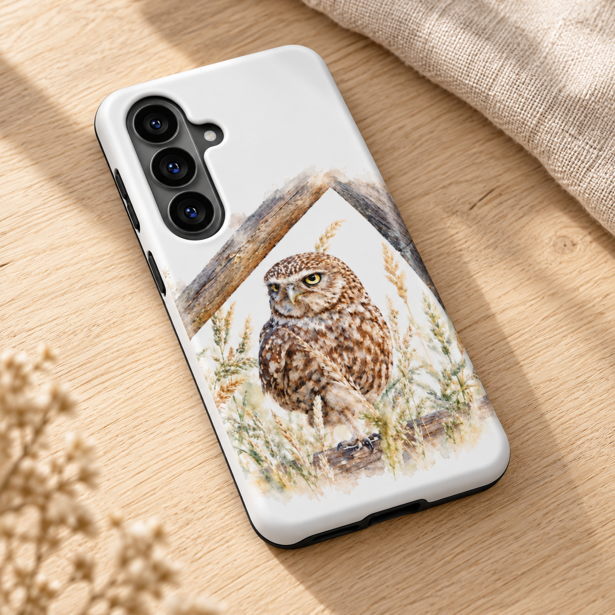 Samsung-hoesje met Steenuil in aquarelstijl, diagonaal op een houten tafel met naturel linnen.