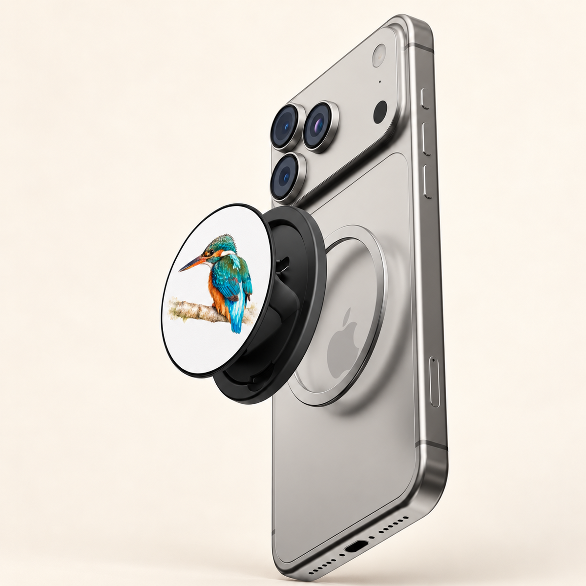 Magnetic phone grip met IJsvogel naast de magnetische ring op de achterkant van een zilveren telefoon, met de bevestiging zichtbaar.