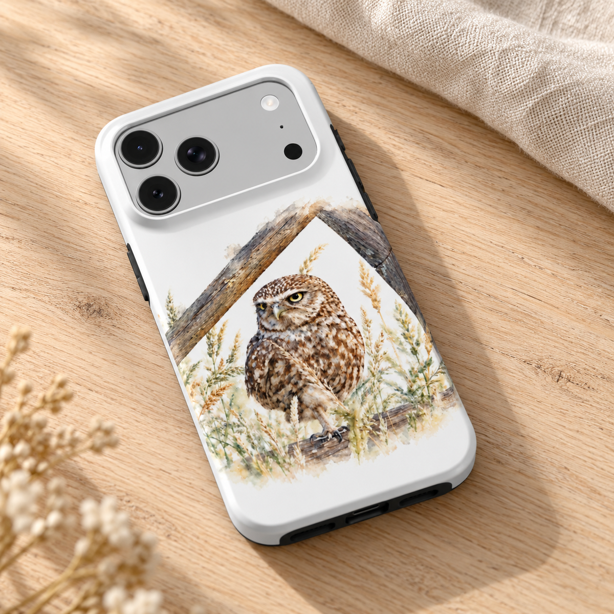 iPhone-hoesje met Steenuil in aquarelstijl, diagonaal op een houten tafel met naturel linnen.