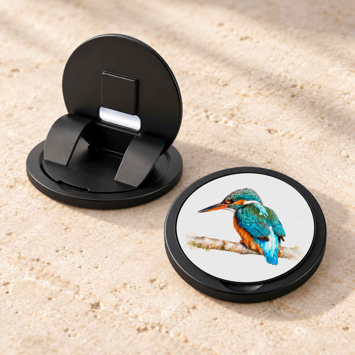 Twee weergaven van de telefoongrip met IJsvogel: het zwarte inklapmechanisme van achteren en de gesloten bedrukte voorkant.