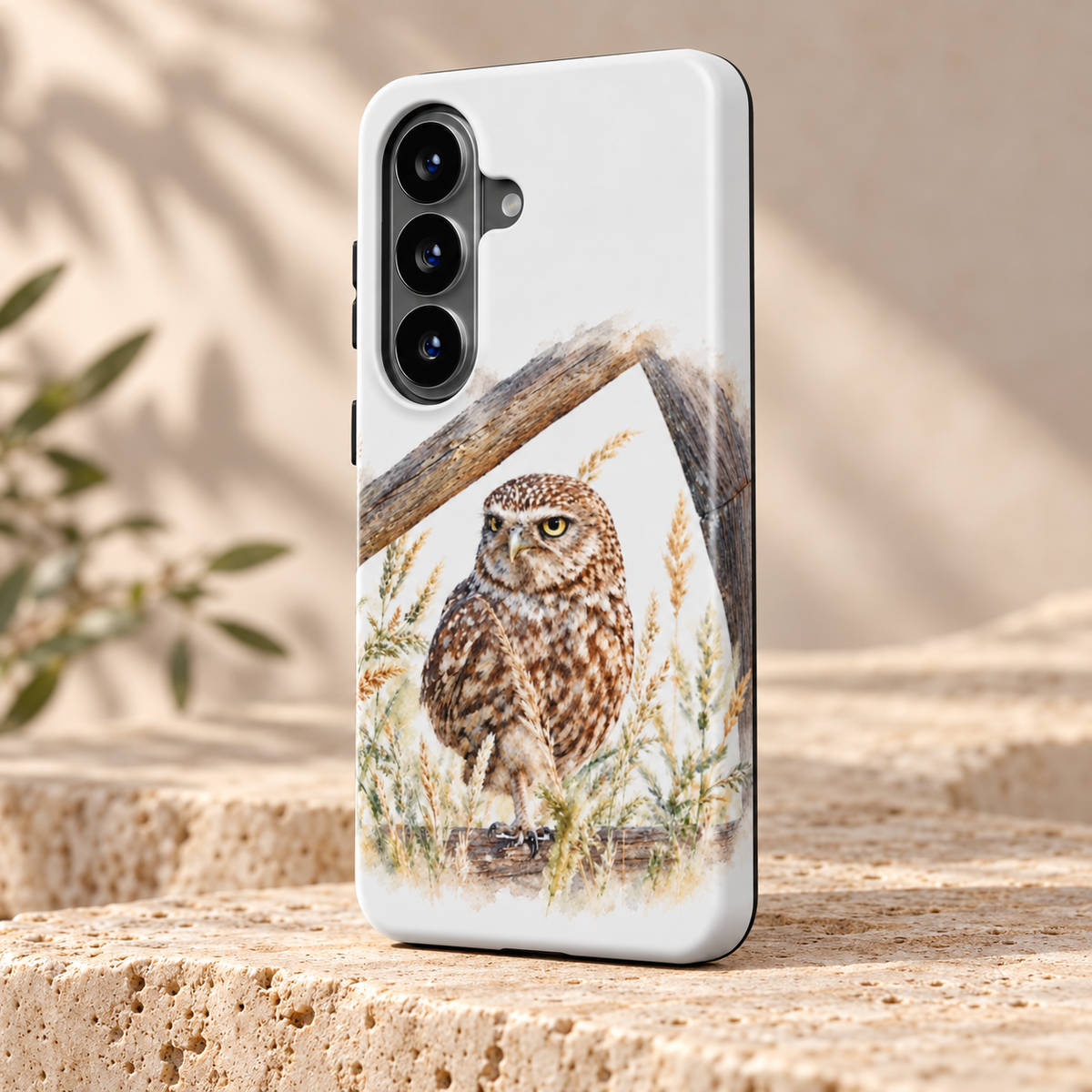 Wit Samsung-hoesje met Steenuil in aquarelstijl, schuin van achteren op een lichte stenen ondergrond.