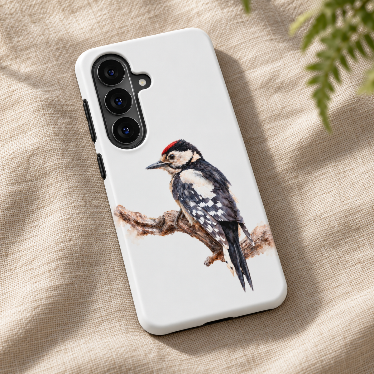 Witte Samsung Tough Case met Grote Bonte Specht in aquarelstijl op een tak, liggend op beige linnen.