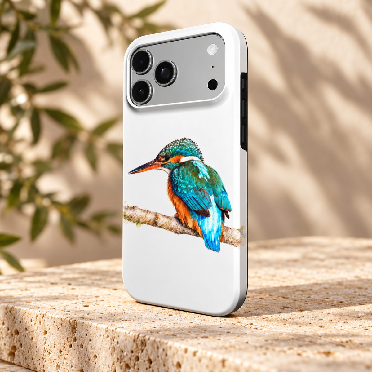 Wit iPhone-hoesje met IJsvogel in aquarelstijl, schuin van achteren op een lichte stenen ondergrond.
